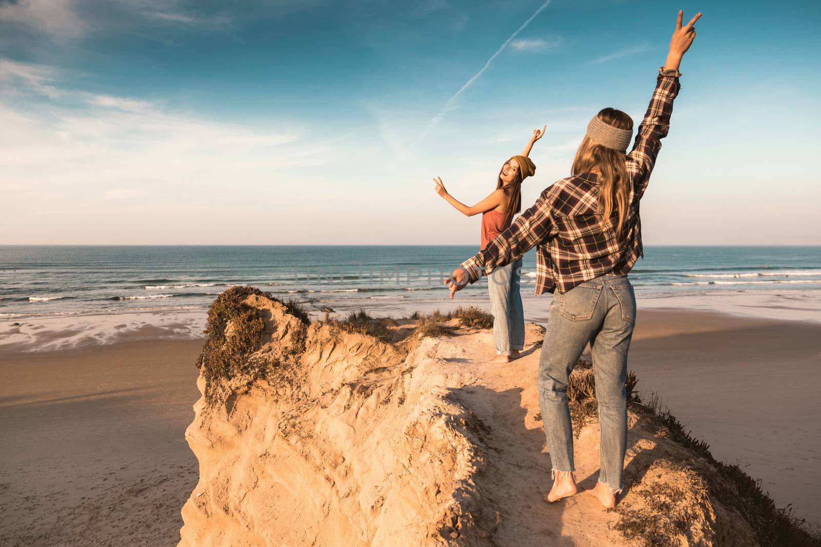 Two best friends near the coastline having fun with arms open