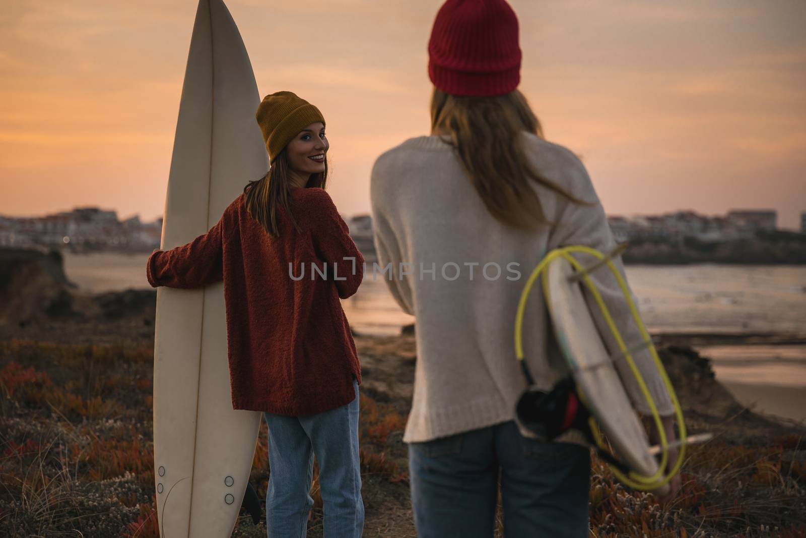 Shot of two female friends holding their surfboards while looking to the ocean