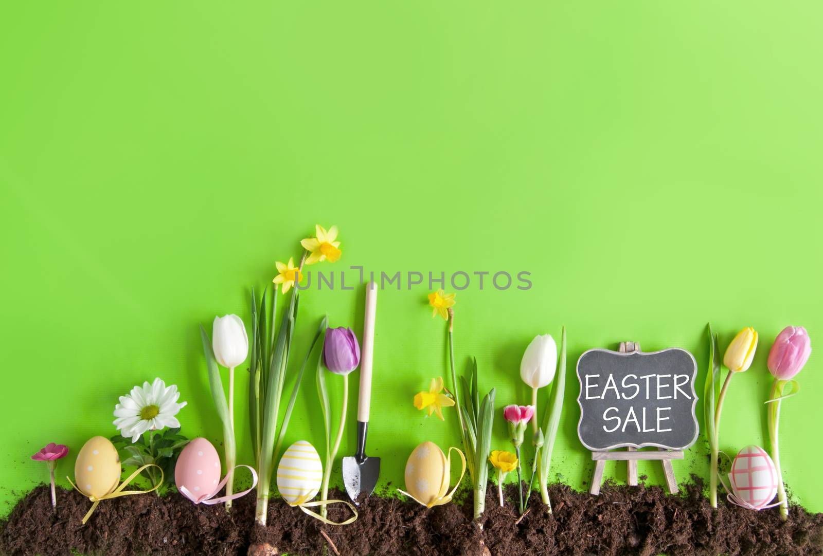 Easter sale sign on a chalkboard on a flower bed background with row of painted eggs amongst flowers