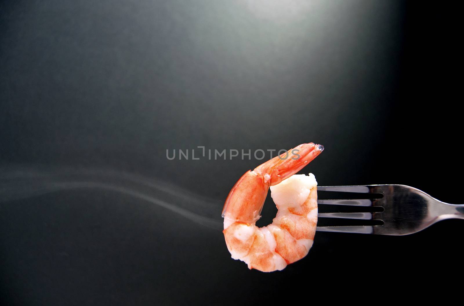 Close up of a cooked prawn on a fork 