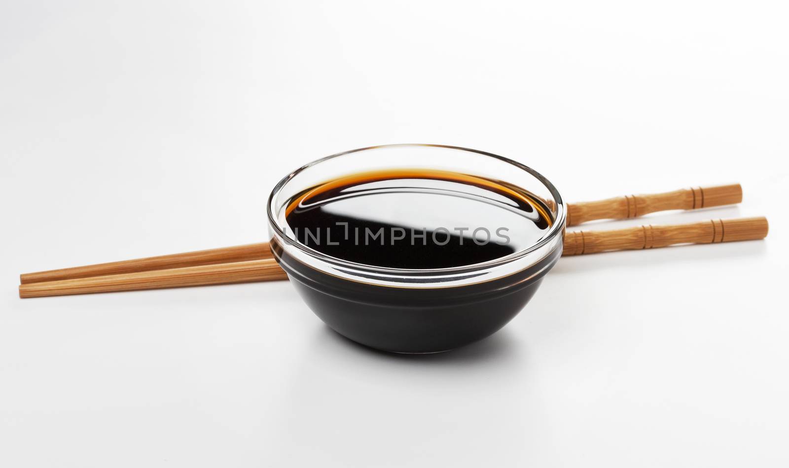 Soy sauce and chopsticks on white background by xamtiw