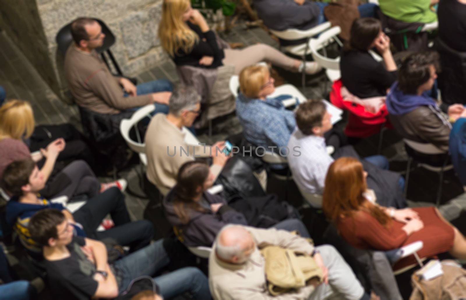 Abowe shot of blured audience in conference hall. Presentation in lecture hall at university workshop. Rear view of unrecognized participant in audience. Scientific conference event.