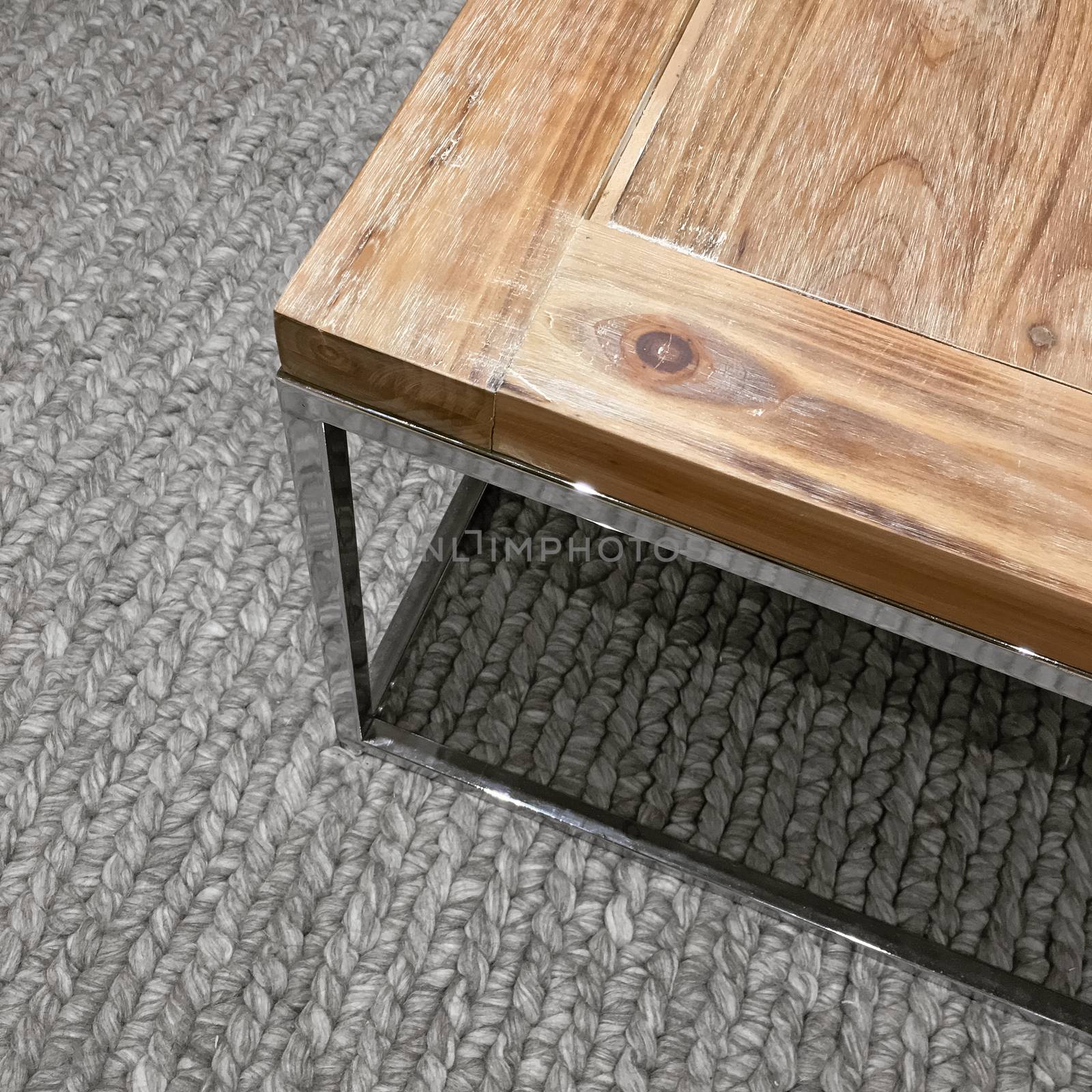 Wooden table with metal frame on gray knitted carpet. Modern design.