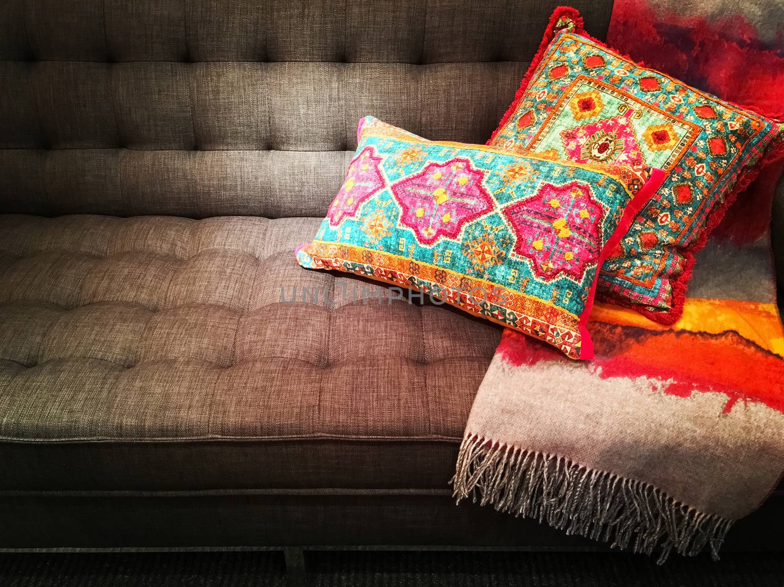 Textile sofa decorated with bright ornate cushions by anikasalsera