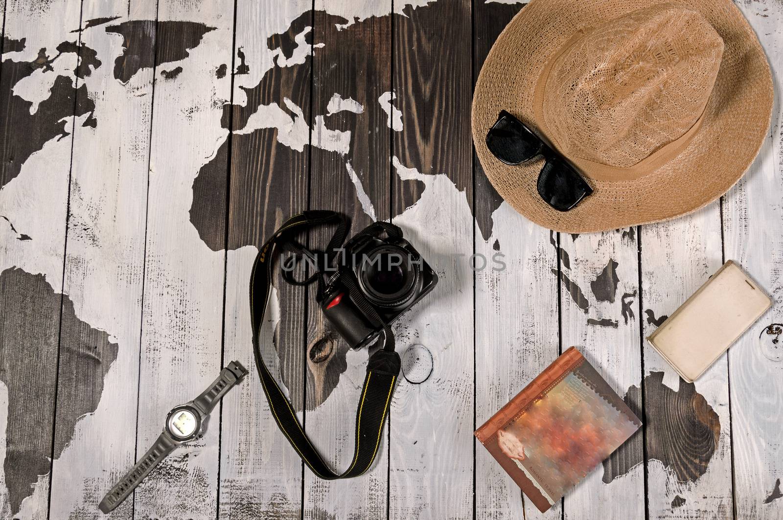 Table with open map showing plans for travelling and related items including watch smartphone sunglasses hat notebook and camera by andre_dechapelle