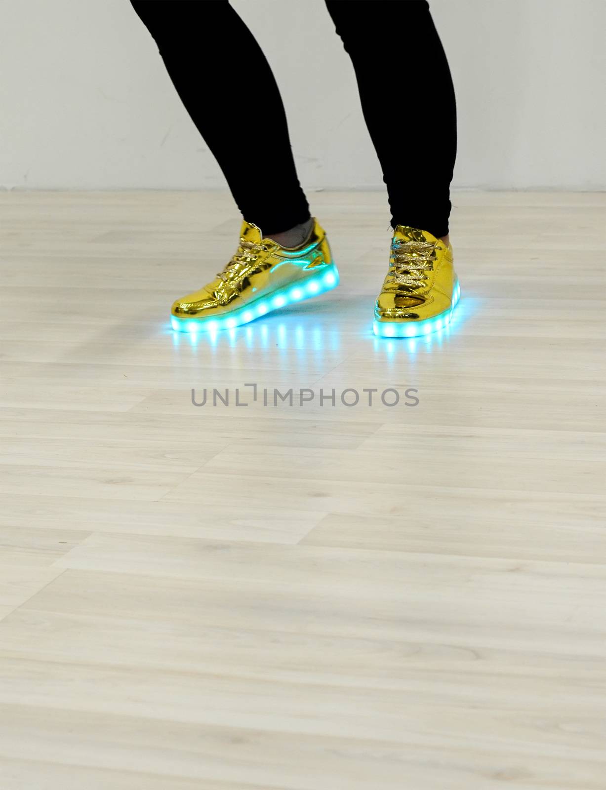 Fashionable sneakers with LED lighting on the legs of a girl with copyspace down. The same color LED lighting sneakers.
