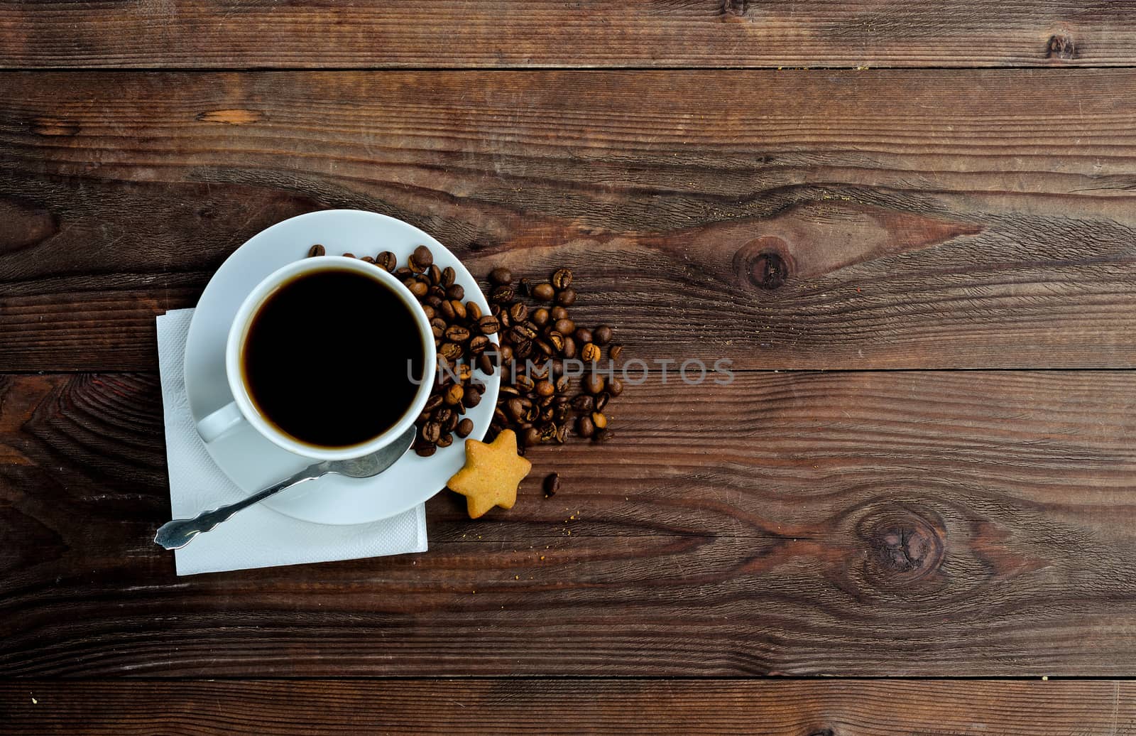 A cup of coffee, coffee beans and one star cookies on wood background