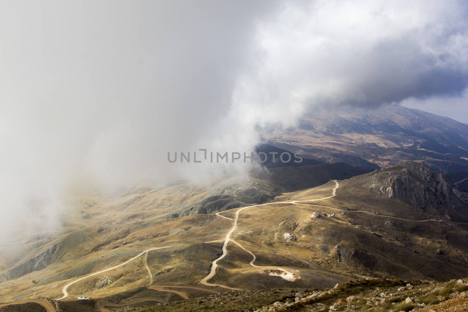 the serpentine road through sunlit mountains. by oaltindag