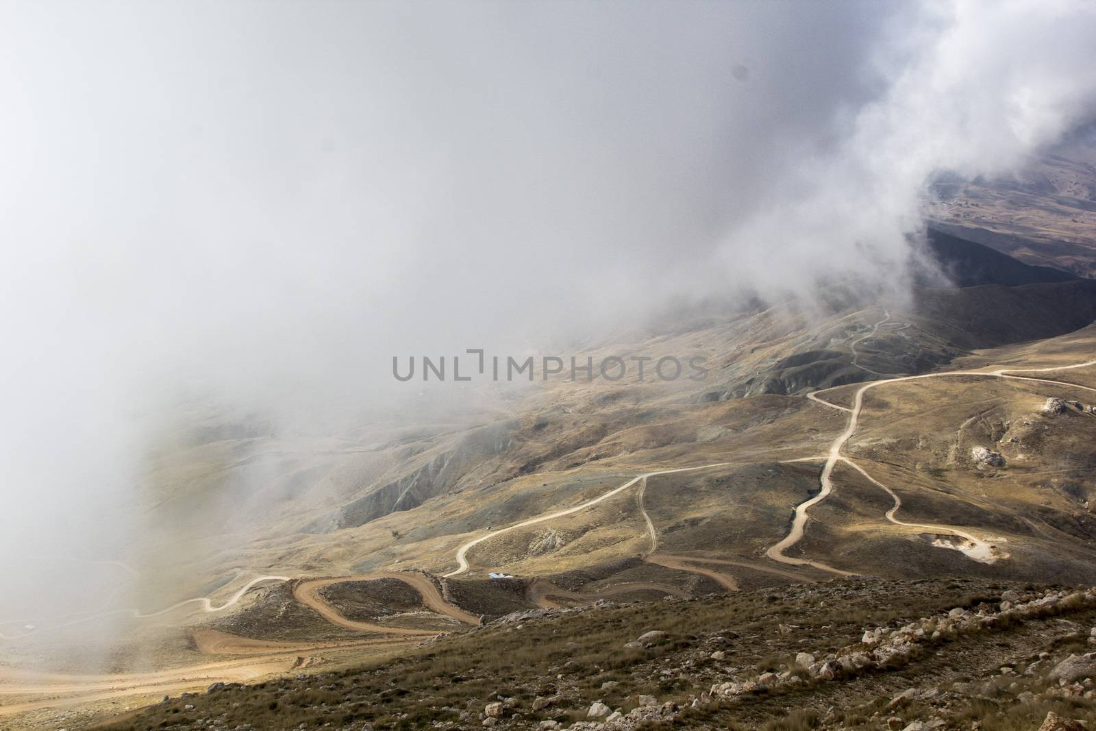 the serpentine road through sunlit mountains. by oaltindag