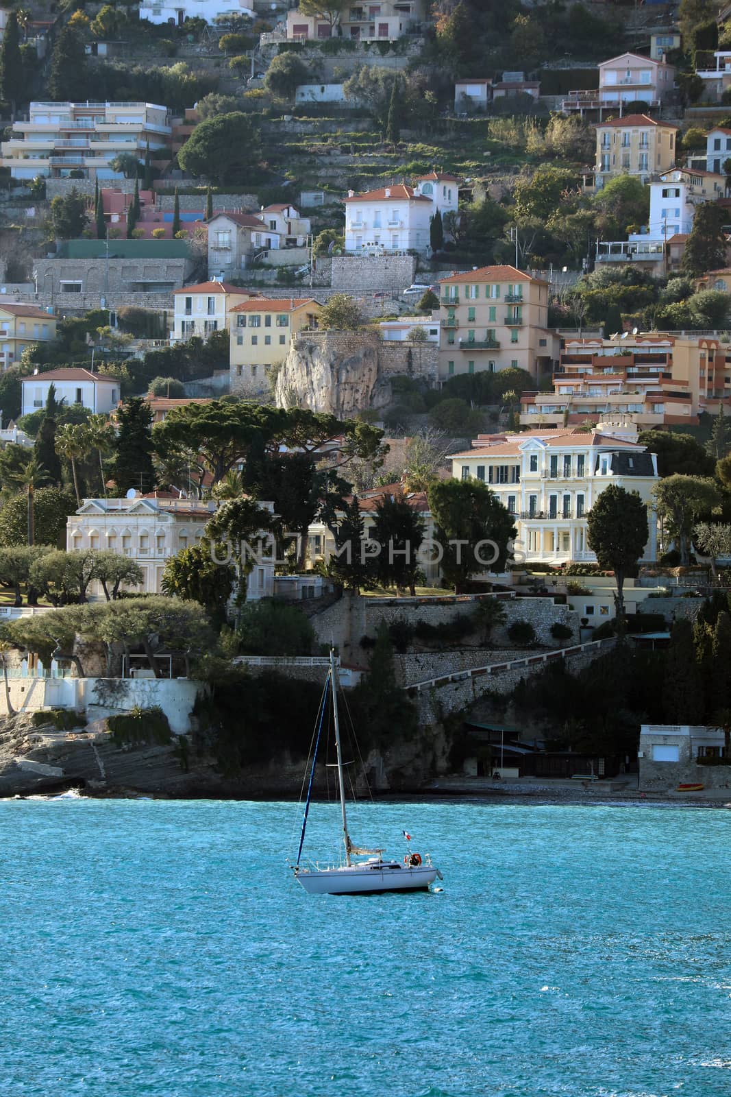 Sailboat With The Beach (La Plage du Buse) And The Luxury Houses of The City of Roquebrune-Cap-Martin in The Background, French Riviera