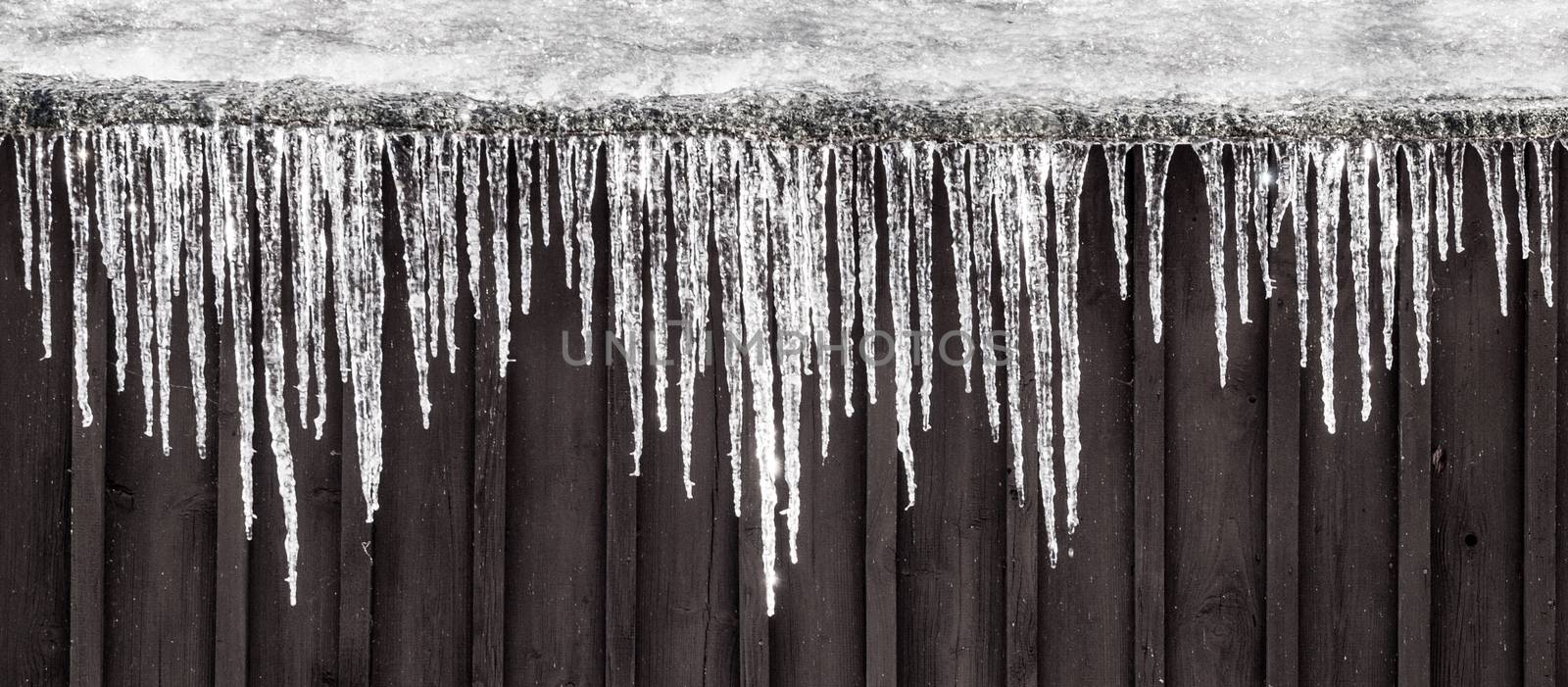 Row of icicles hanging on the roof. Rural winter scene by pyty