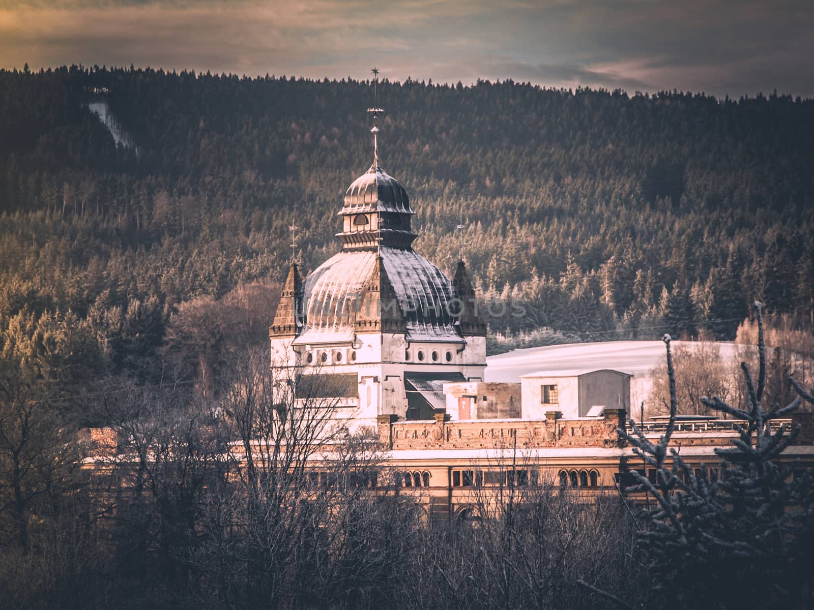 Old mountain factory with ornamental dome in winter landscape. Vintage style image.