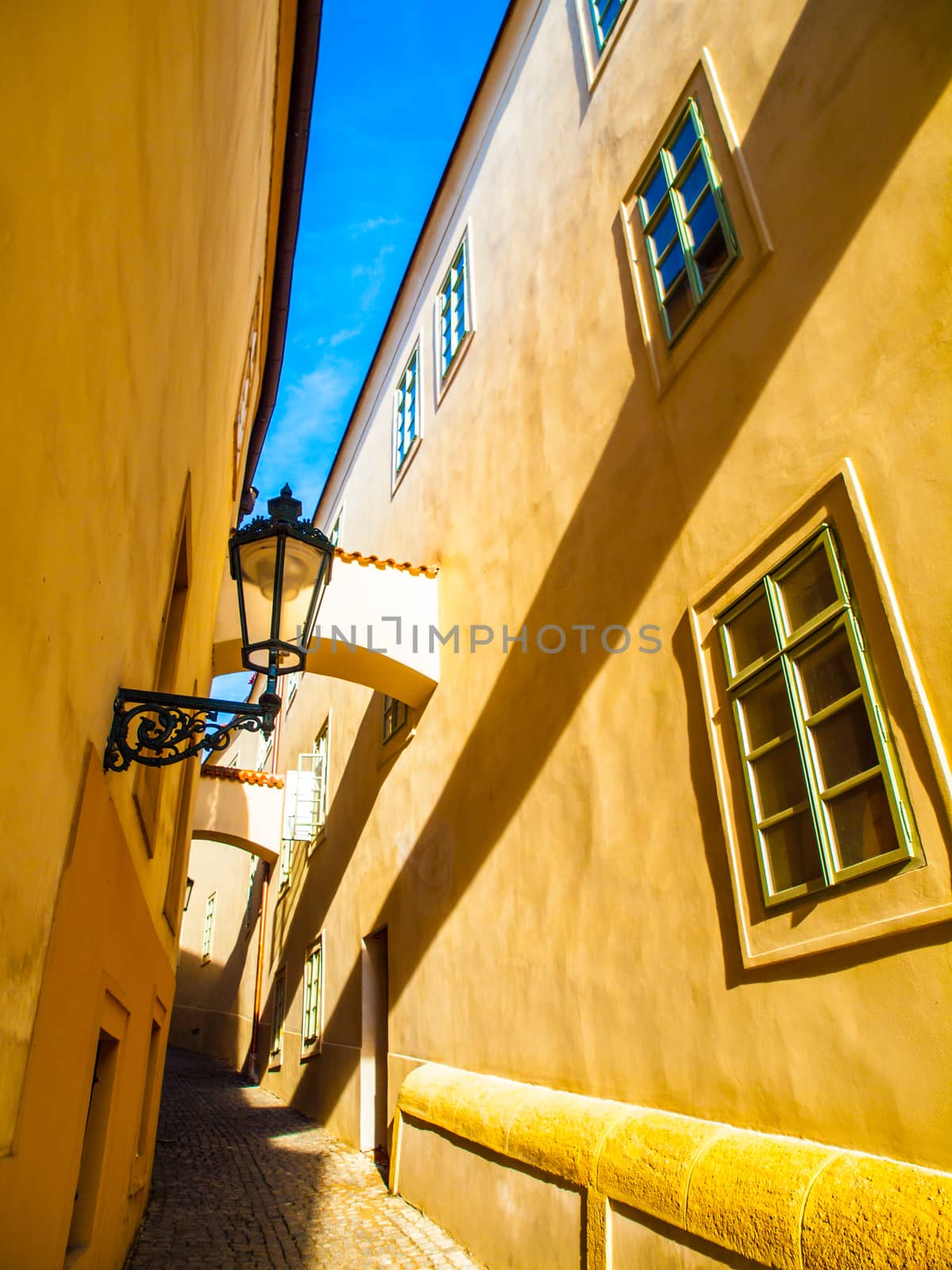Morning Prague scene. Sunlit and long shadows on the wall with gas street lamp, Thunovska Street, Lesser Town, Prague, Czech Republic.