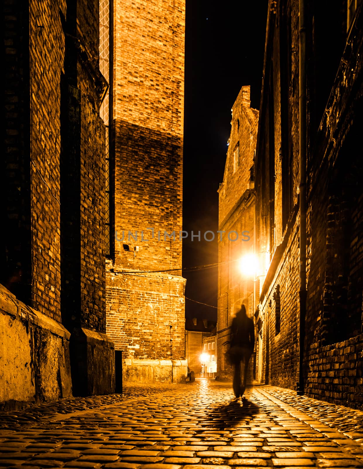 Cobbled street of Old Town with dark blurred silhouette of person. Evokes Jack the Ripper.