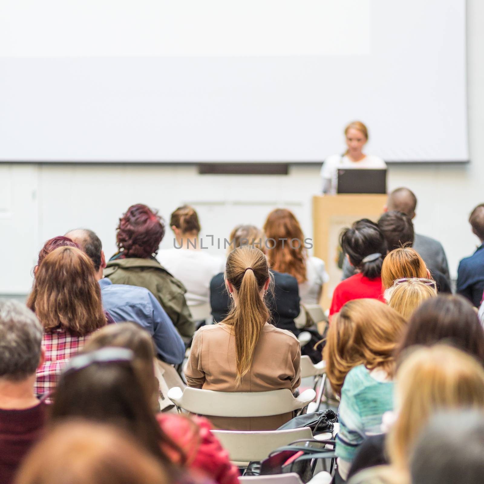 Woman giving presentation in lecture hall at university. by kasto