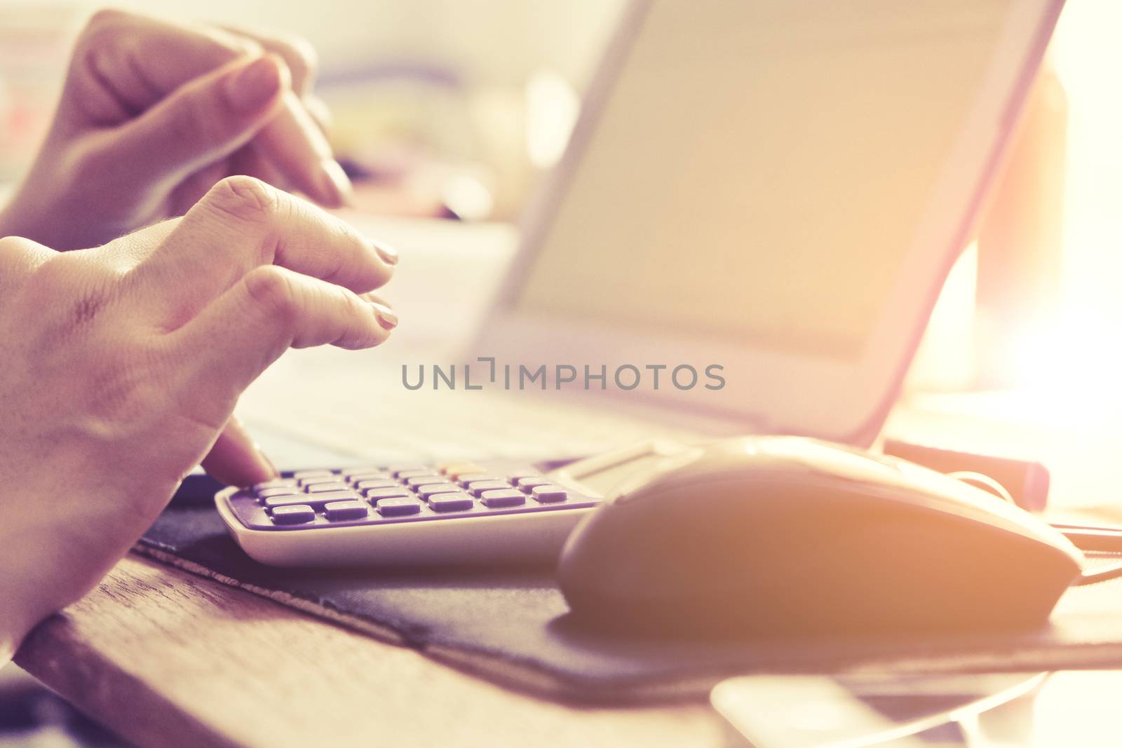 Close-up of female hands using laptop computer, working on laptop with flare light background. Searching Internet ,Businesswoman working at home office