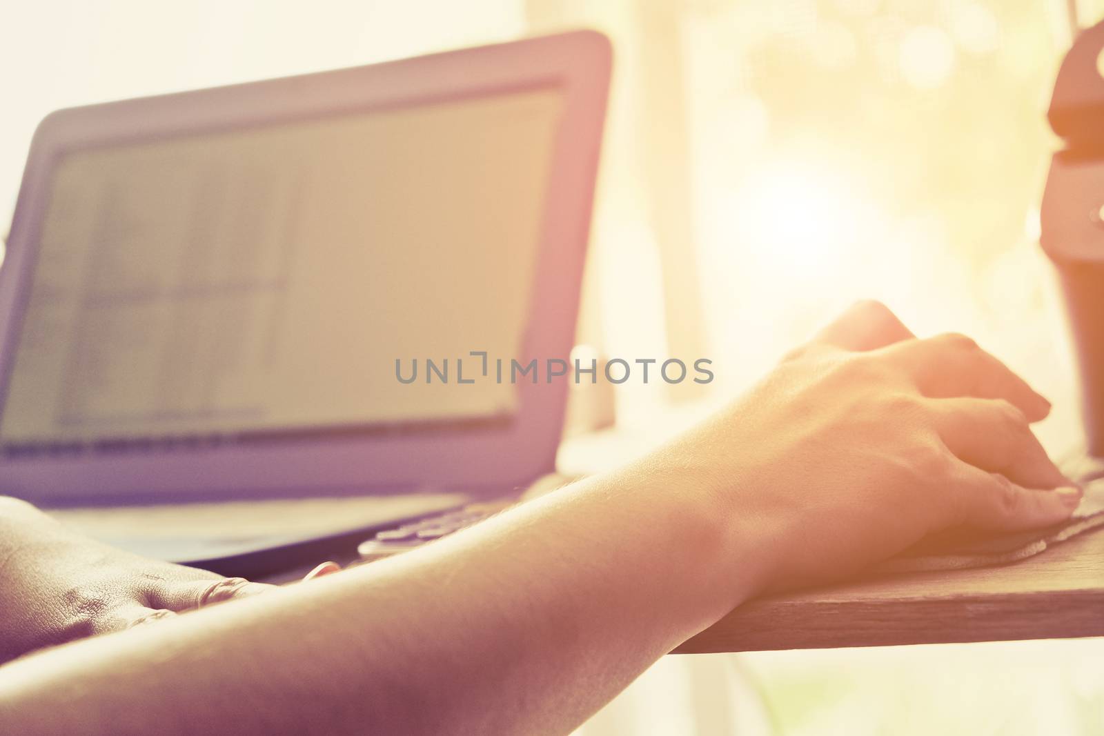 Close-up of female hands using laptop computer, working on laptop with flare light background. Searching Internet ,Businesswoman working at home office