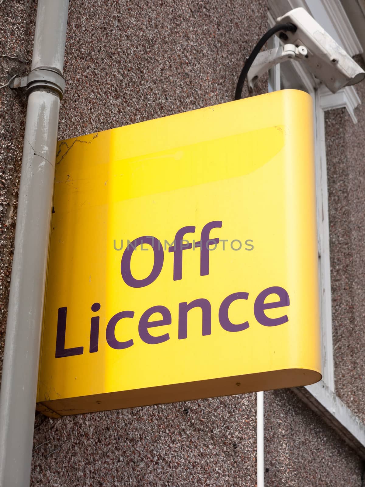 a yellow street and shop sign for the off licence; Essex; UK
