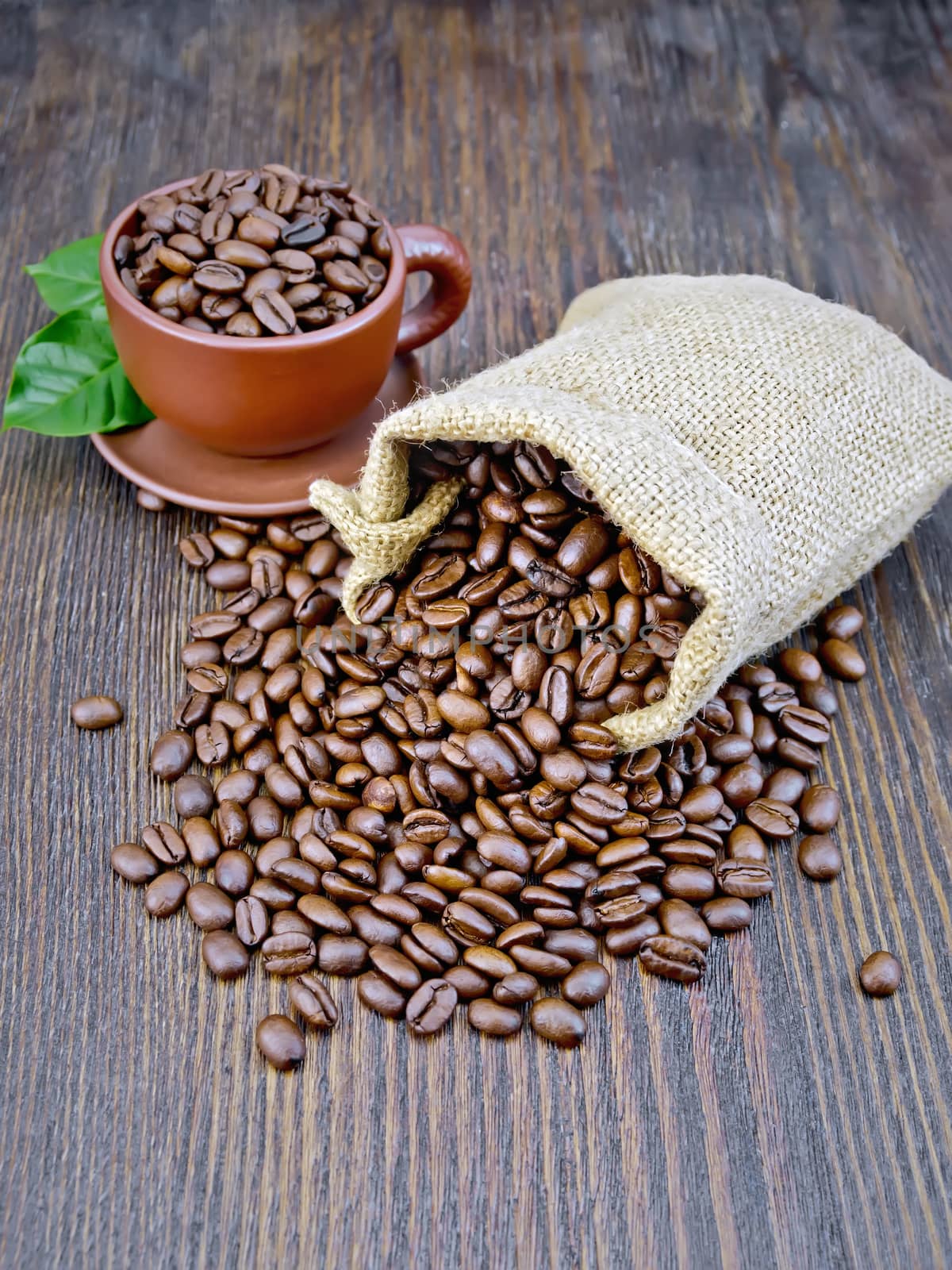 Bag of black coffee beans, brown cup on the background of a wooden board