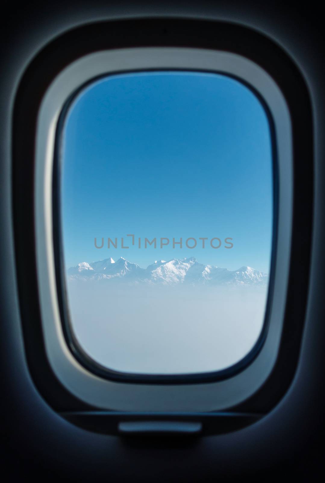 Airplane passenger window with a view on the Himalayas during a flight from Kathmandu to Pokhara in Nepal