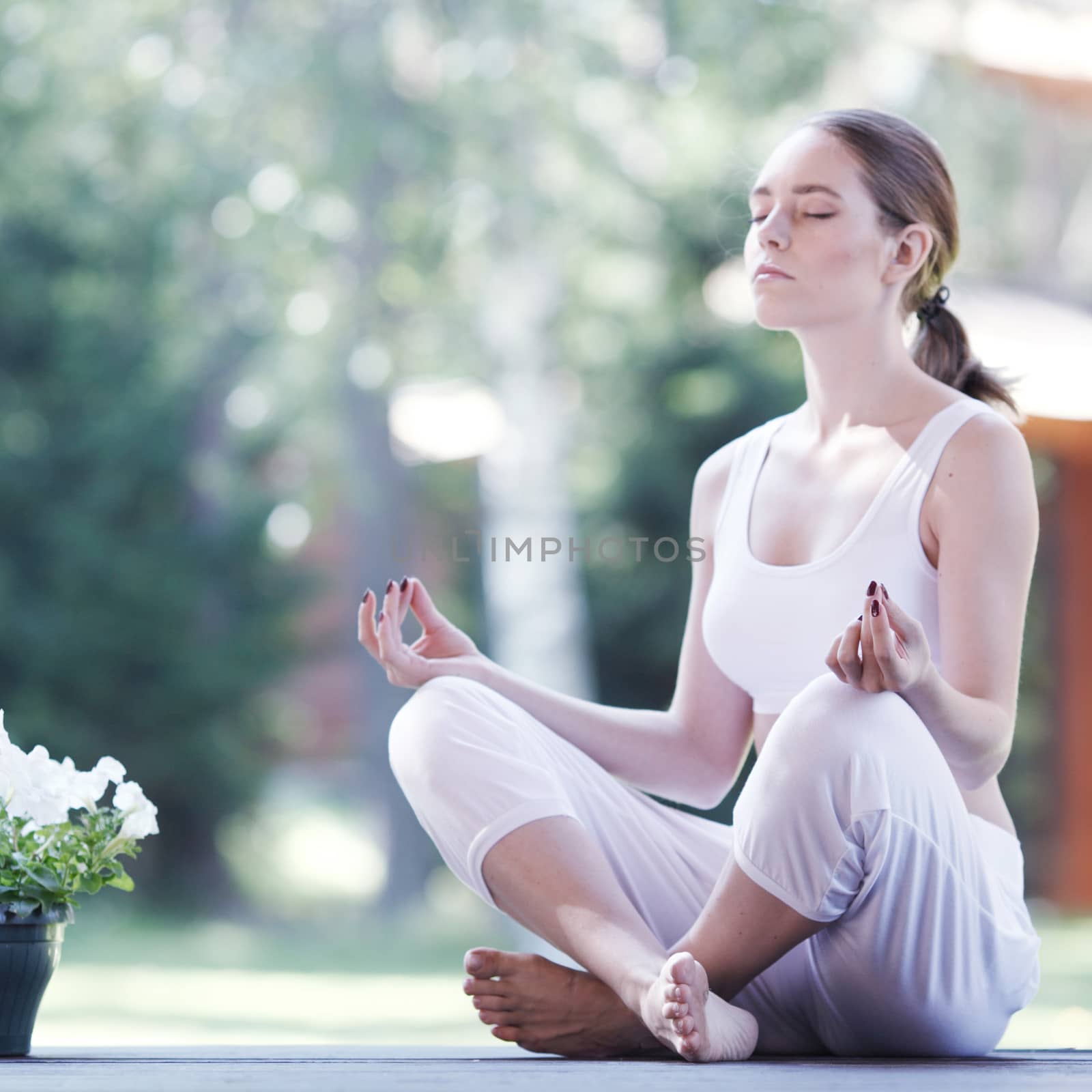 Young woman doing yoga lotus exercise outdoors