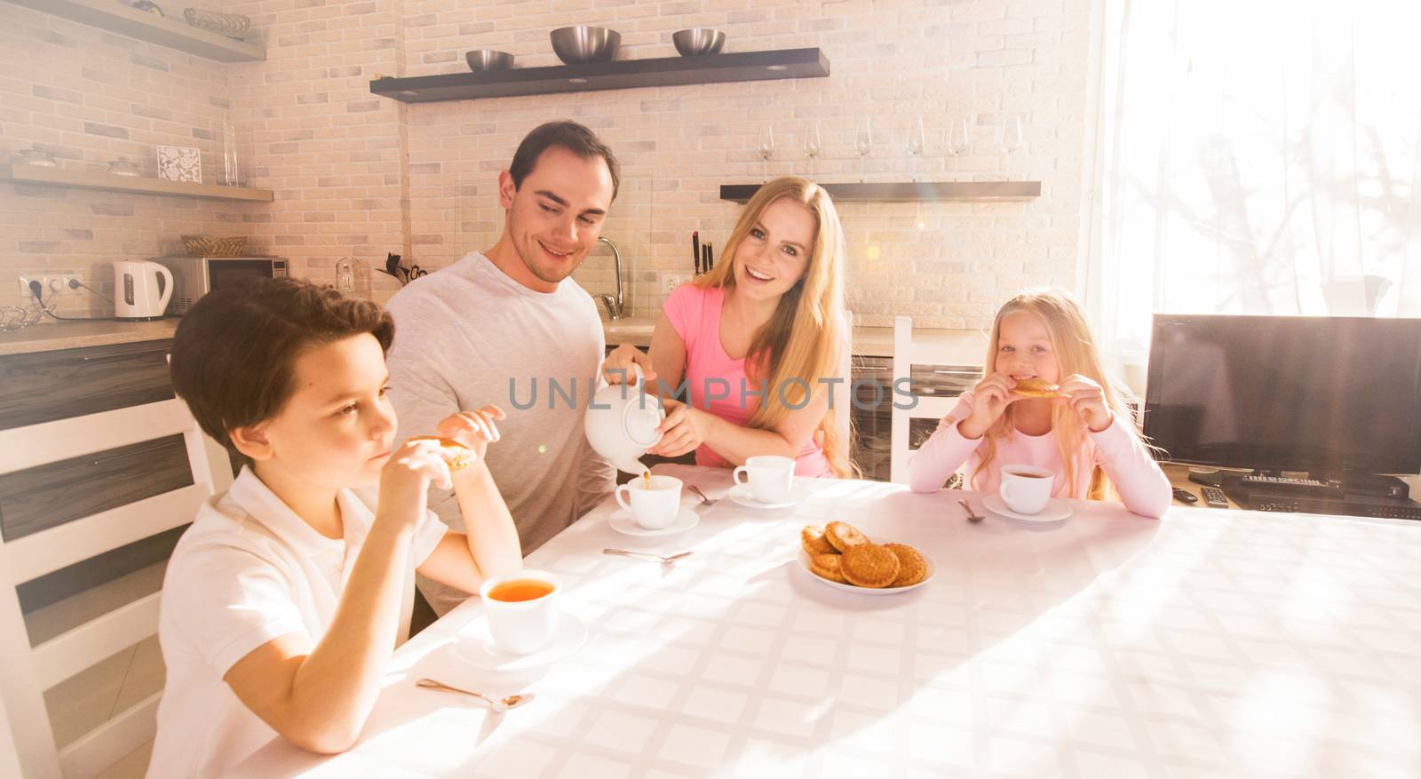 Family smiling having breakfast in kitchen at sunny day