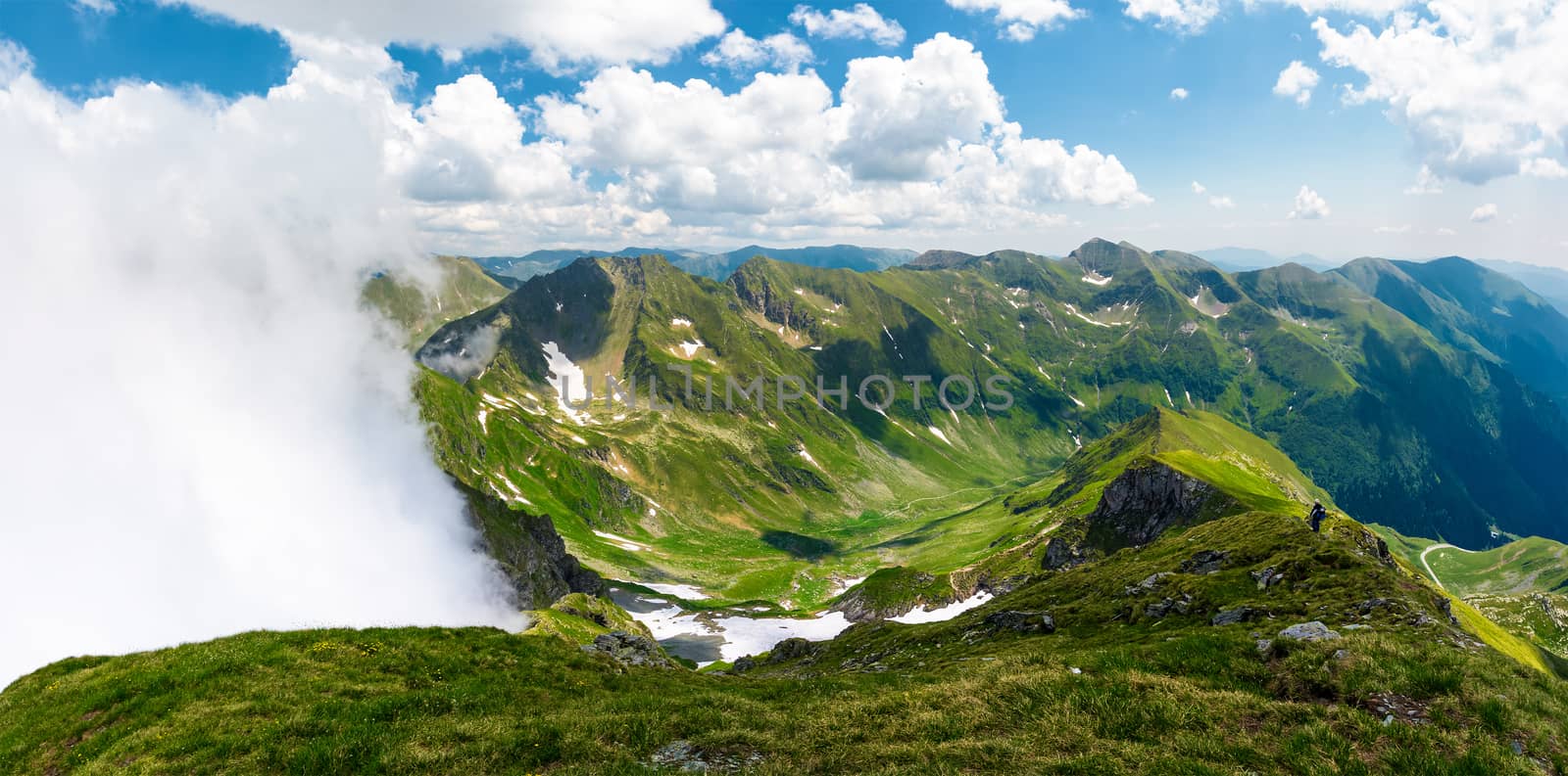 mountainous panorama with rising clouds. beautiful landscape with some snow on grassy hillsides. popular destination for hiking in Fagaras mountains of Romania