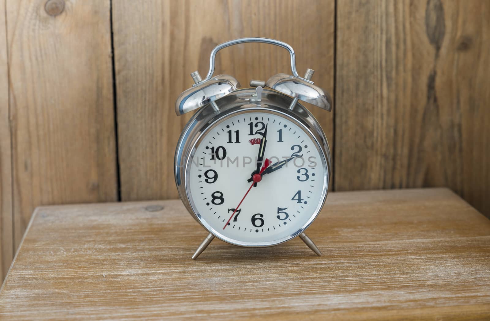 An old fashioned silver coloured bed side analogue pre digital alarm clock