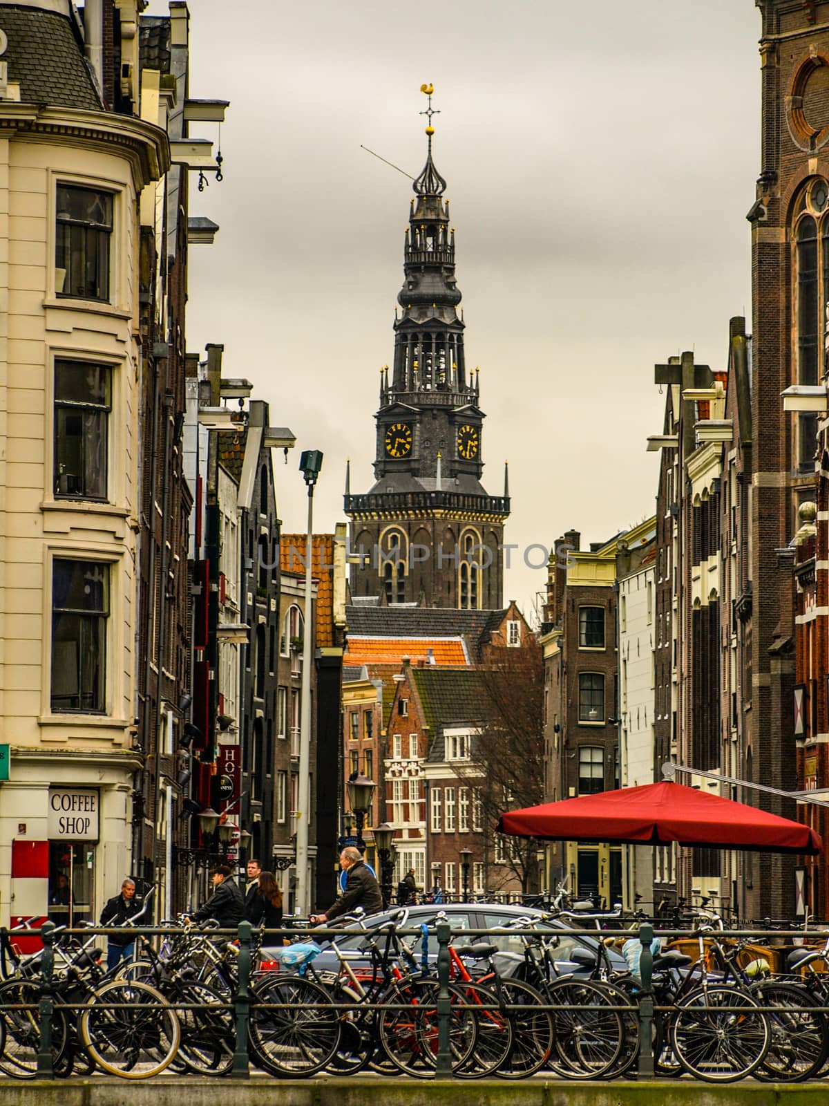 A lot of bicycles parked in the street of Amsterdam. Church tower on a background, Netherlands.