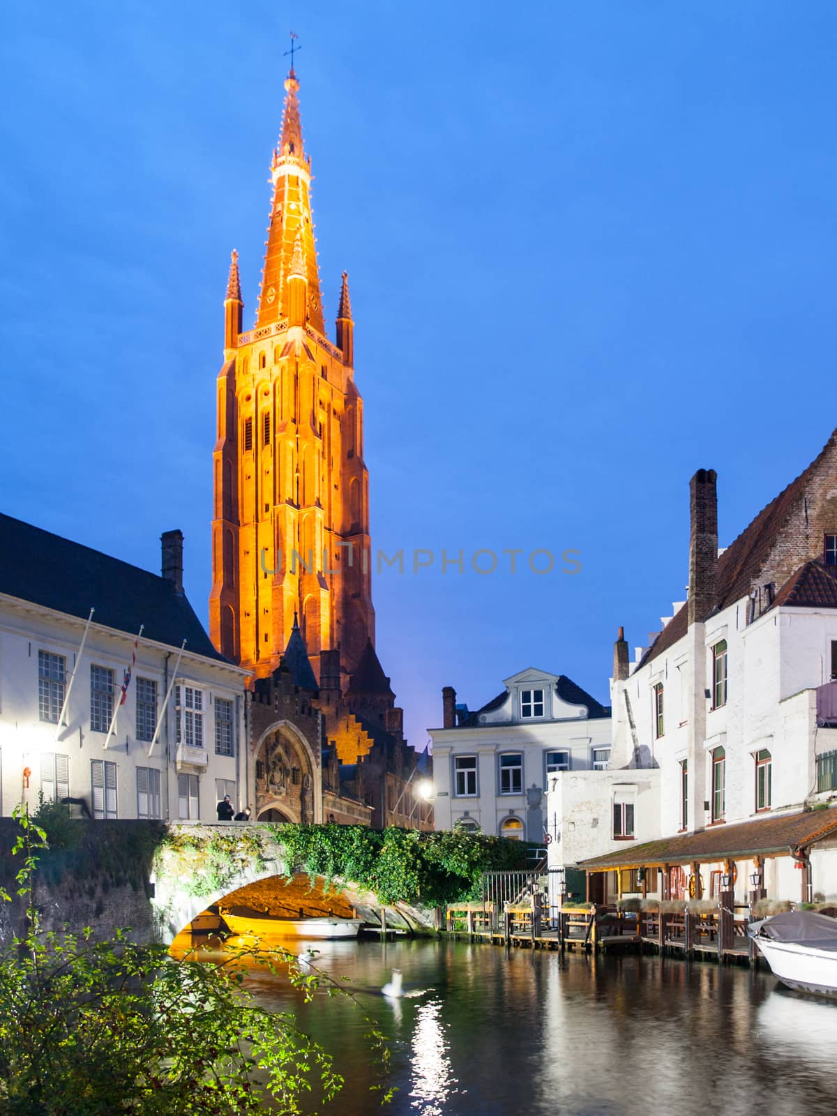 Church of Our Lady and bridge over water canal by night, Bruges, Belgium.