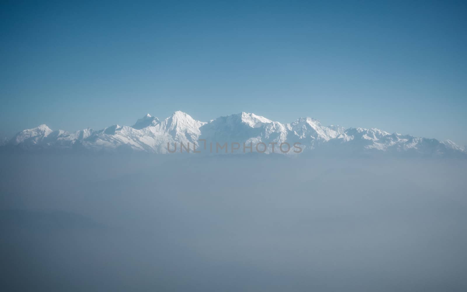 The Himalayas as seen from an airplane in Nepal. Layer of clouds beneath the mountain tops.