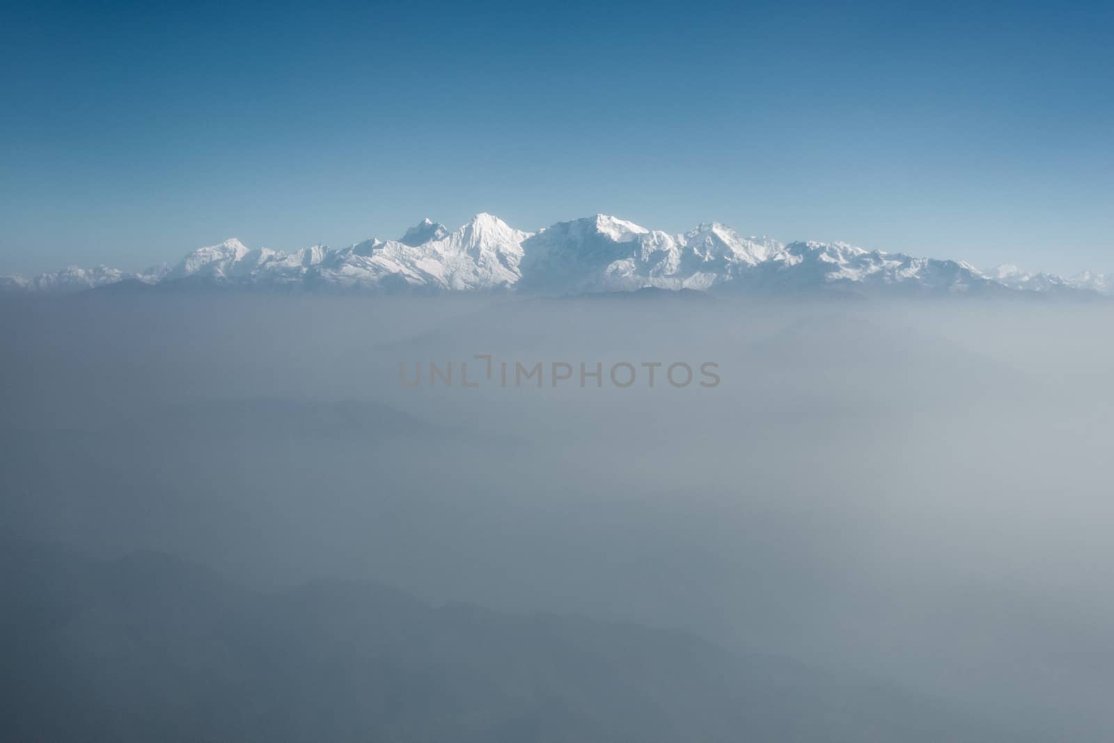 The Himalayas as seen from an airplane in Nepal. Layer of clouds beneath the mountain tops.
