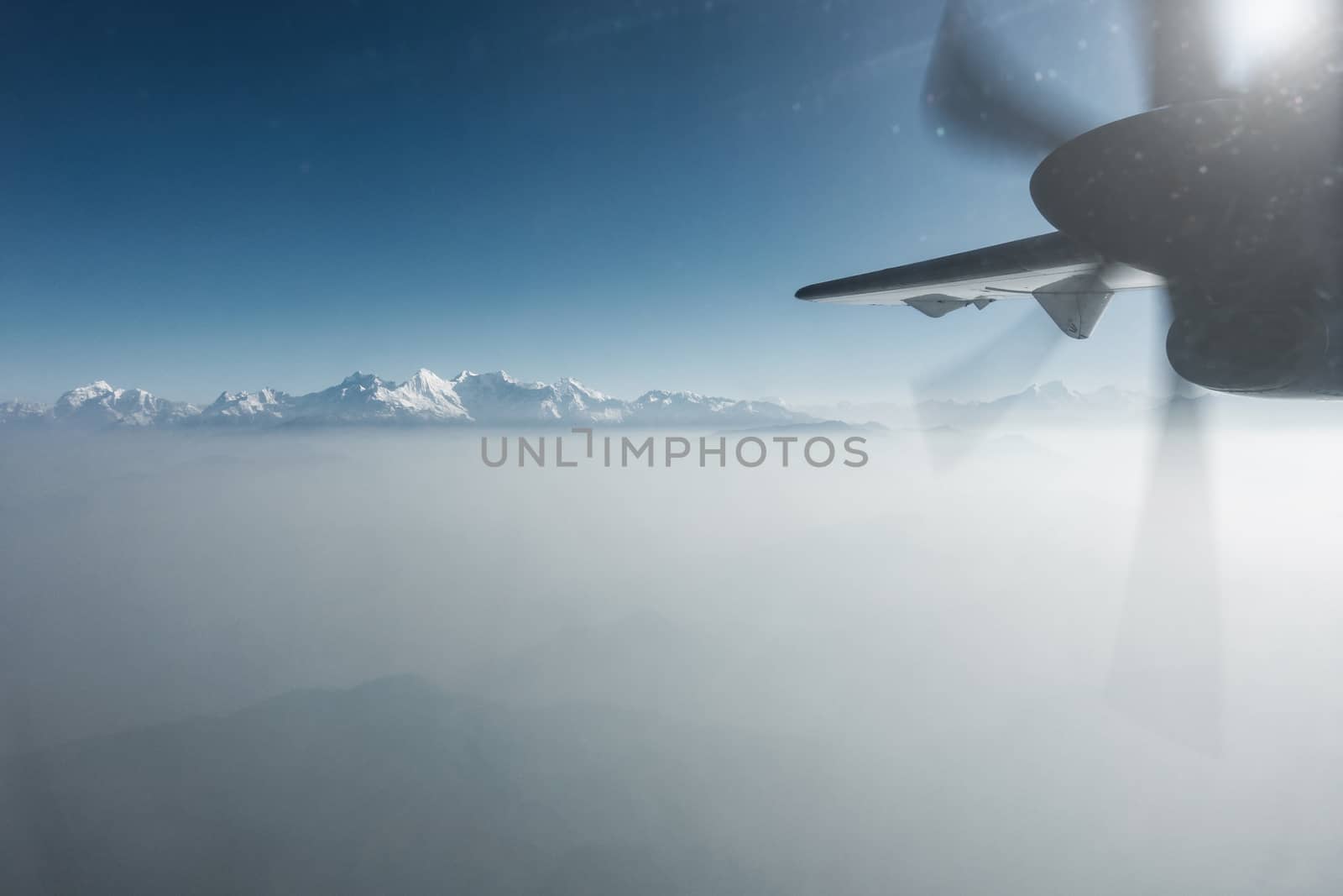 The Himalayas as seen from a propeller plane in Nepal. Layer of clouds beneath the mountain tops.