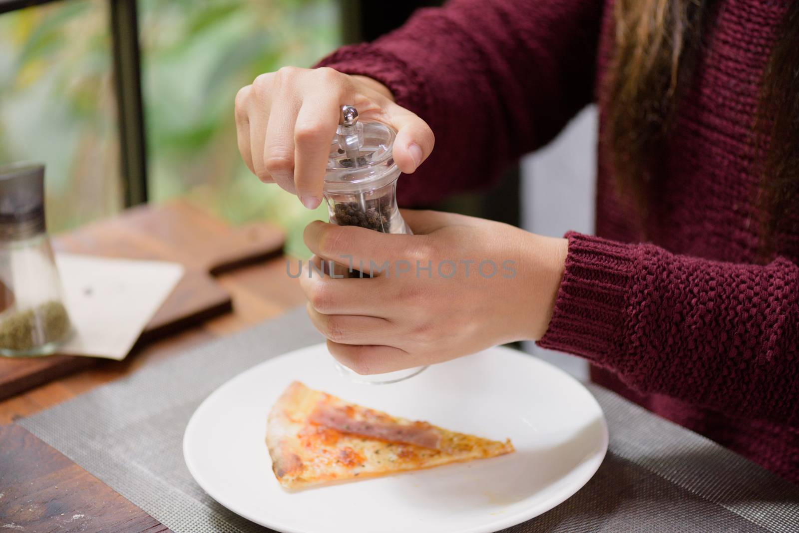 Woman hands using black pepper and salt shaker on the slices of  by spukkato