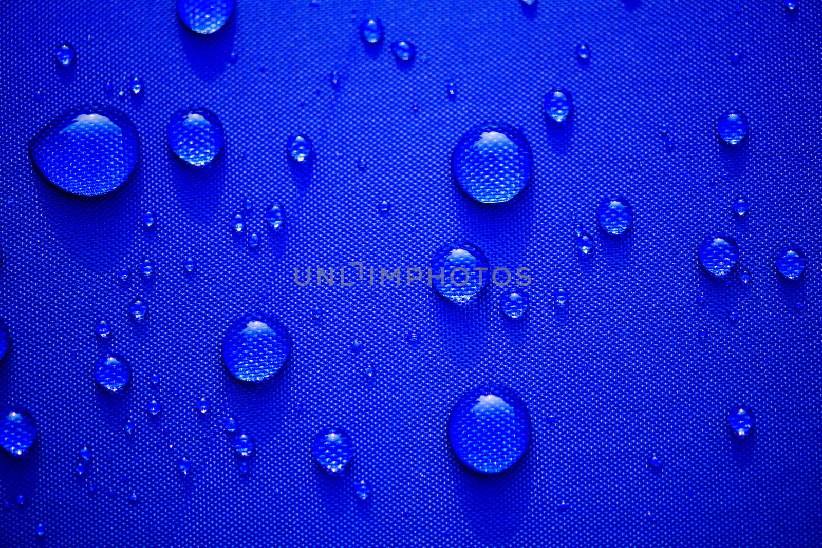 Close up Water drops pattern over a blue waterproof cloth background. World Water Day concept.