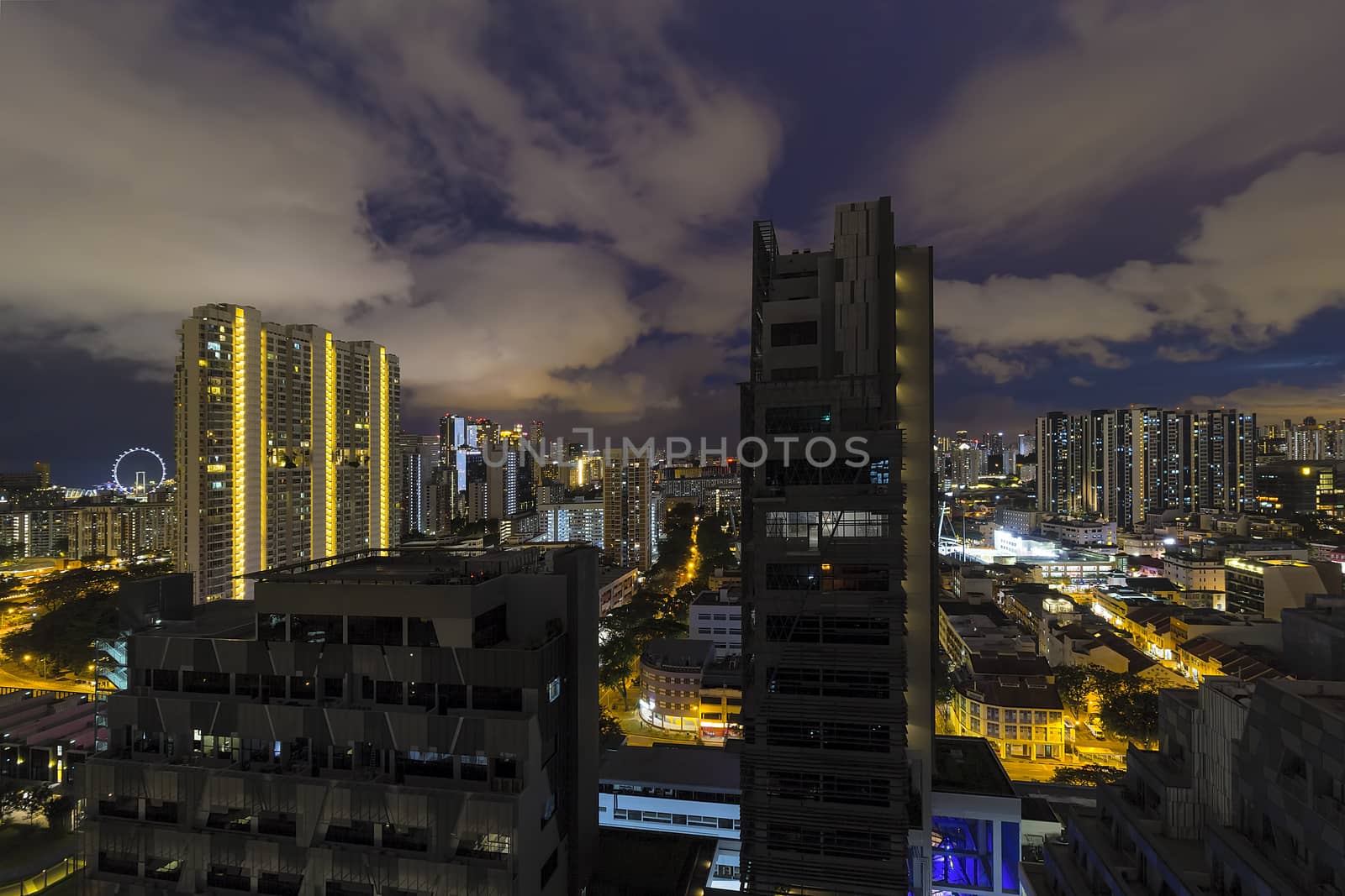 Singapore cityscape with rooftop view of apartment buildings with dramatic cloudy night sky