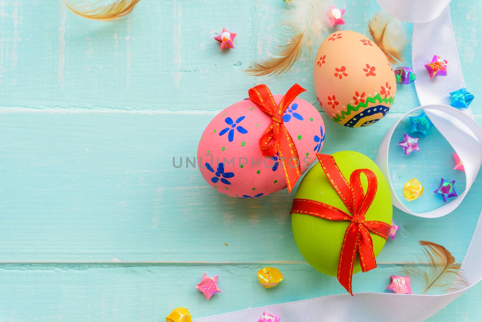 Happy easter! Colorful of Easter eggs with red ribbon and colorful of paper flower and paper star on pastel color bright green and white wooden background.