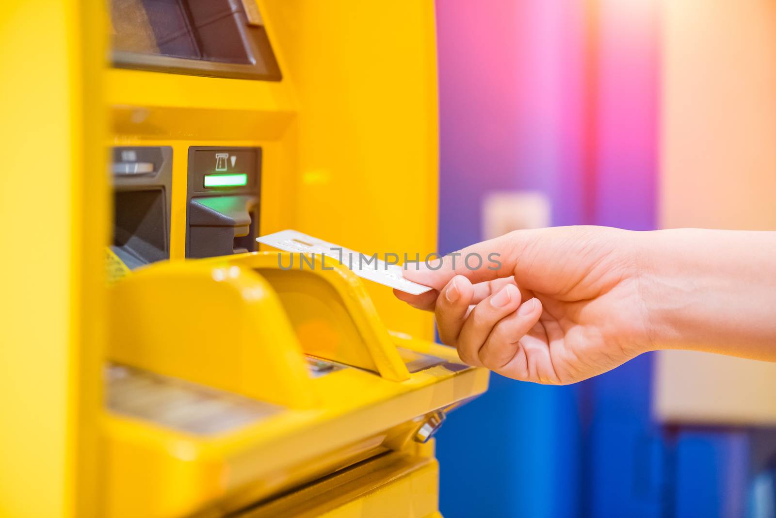 Closeup woman hand inserting debit card into an ATM machine.
