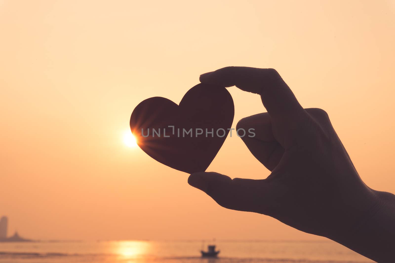 Close up and Silhouette of hand holding red heart during sunset background. Happy, Love, Valentine's day idea, sign, symbol, concept.