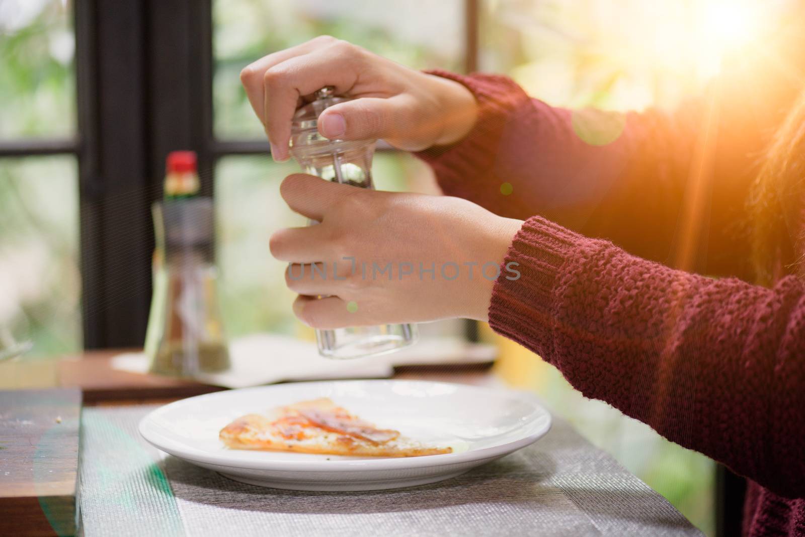 Woman hands using black pepper and salt shaker on the slices of  by spukkato