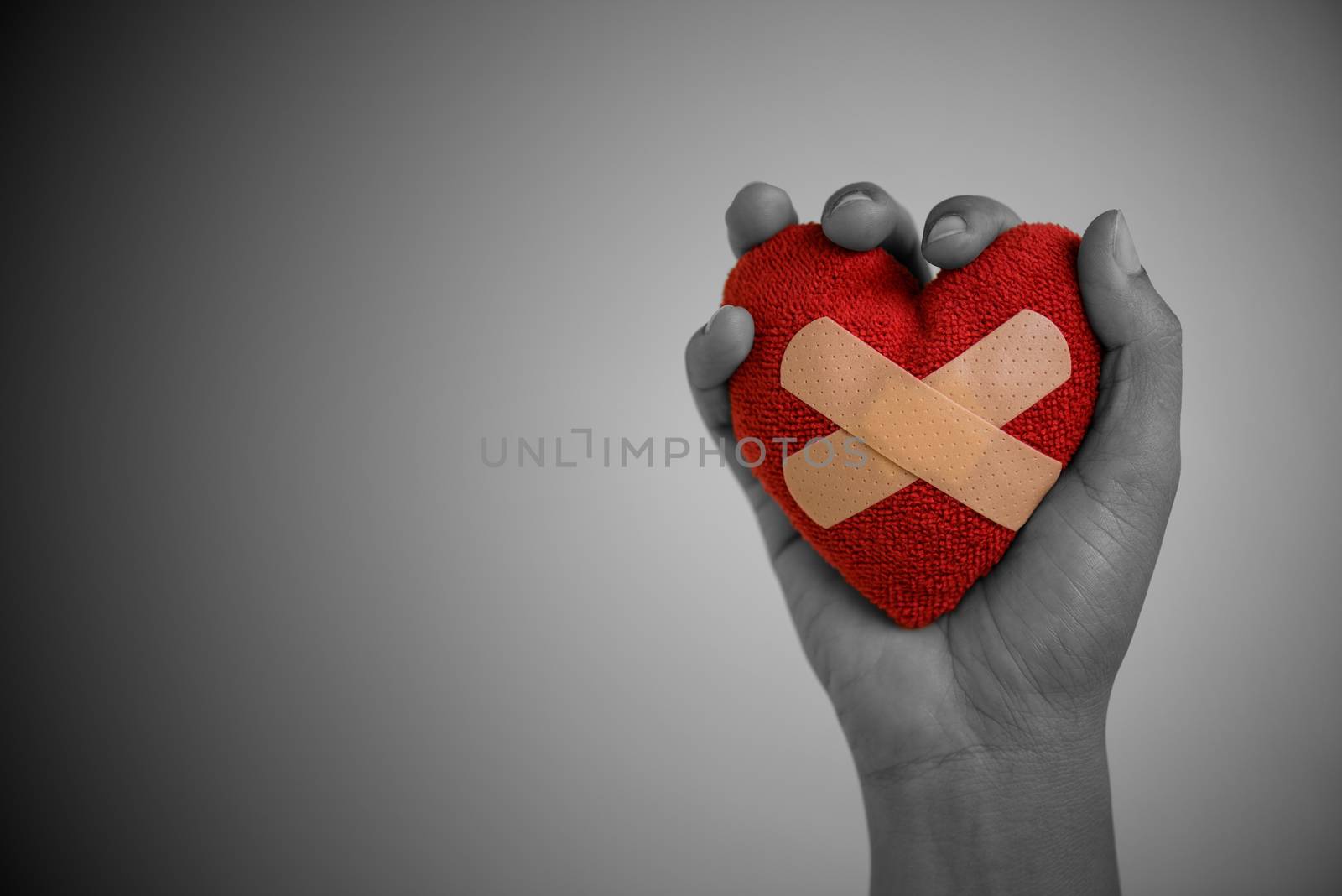 Close up Young woman hand holding red heart glued by Cushioned P by spukkato
