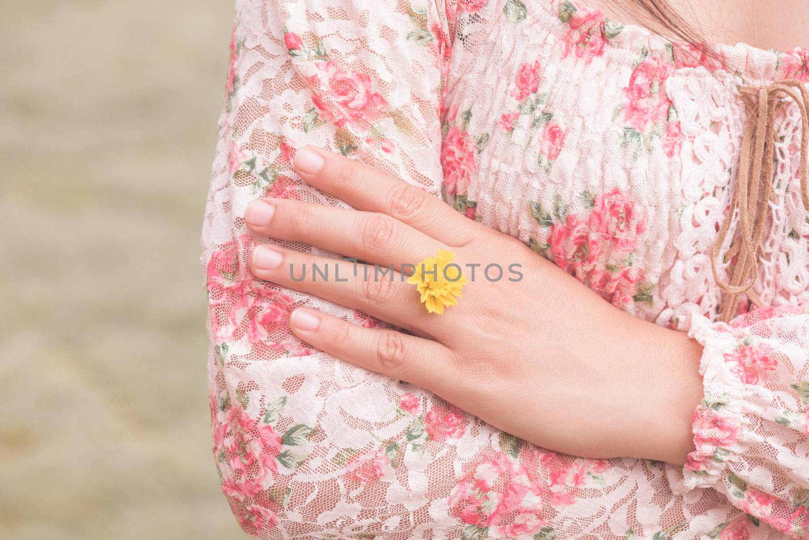 Young woman hand wearing Yellow flower represent of wedding ring on grass green background. Broken hearted, Love forever, Wedding and Valentines day concept.