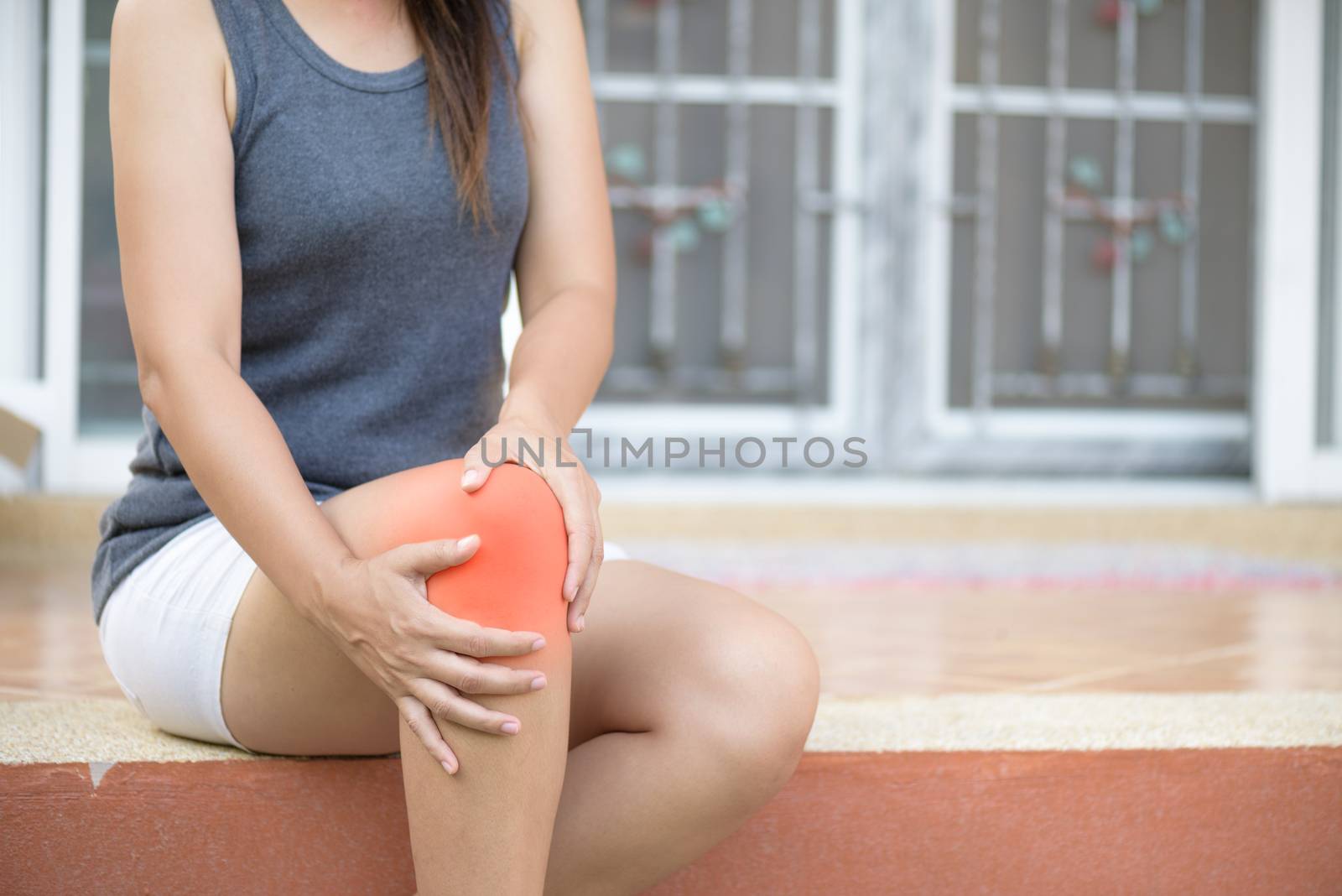 Closeup young woman feeling pain in her knee at home. Healthcare and medical concept.