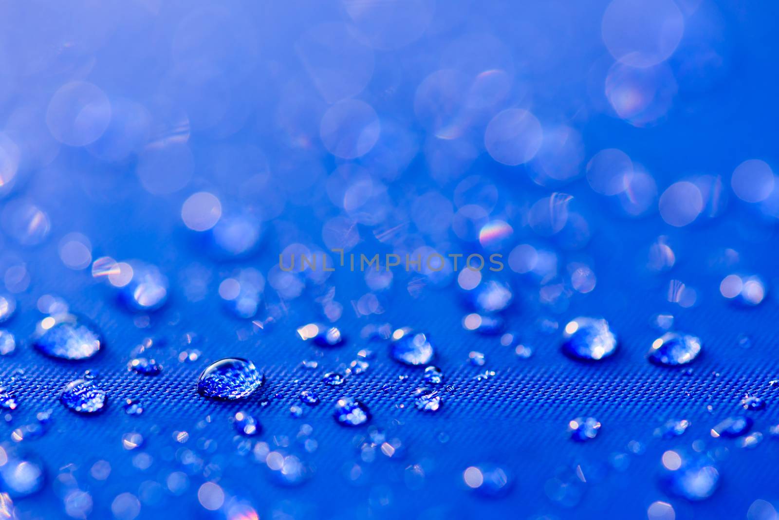 Close up Water drops pattern over a blue waterproof cloth background. World Water Day concept.