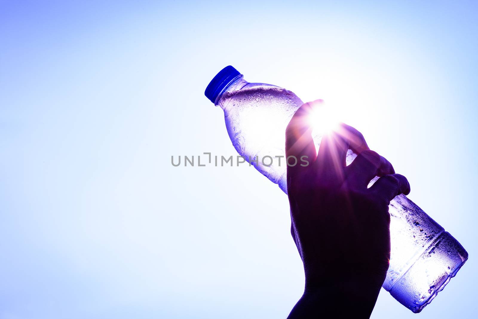 Silhouette of closeup Woman's hand holding plastic water bottle over sunlight effect. World Water Day concept.
