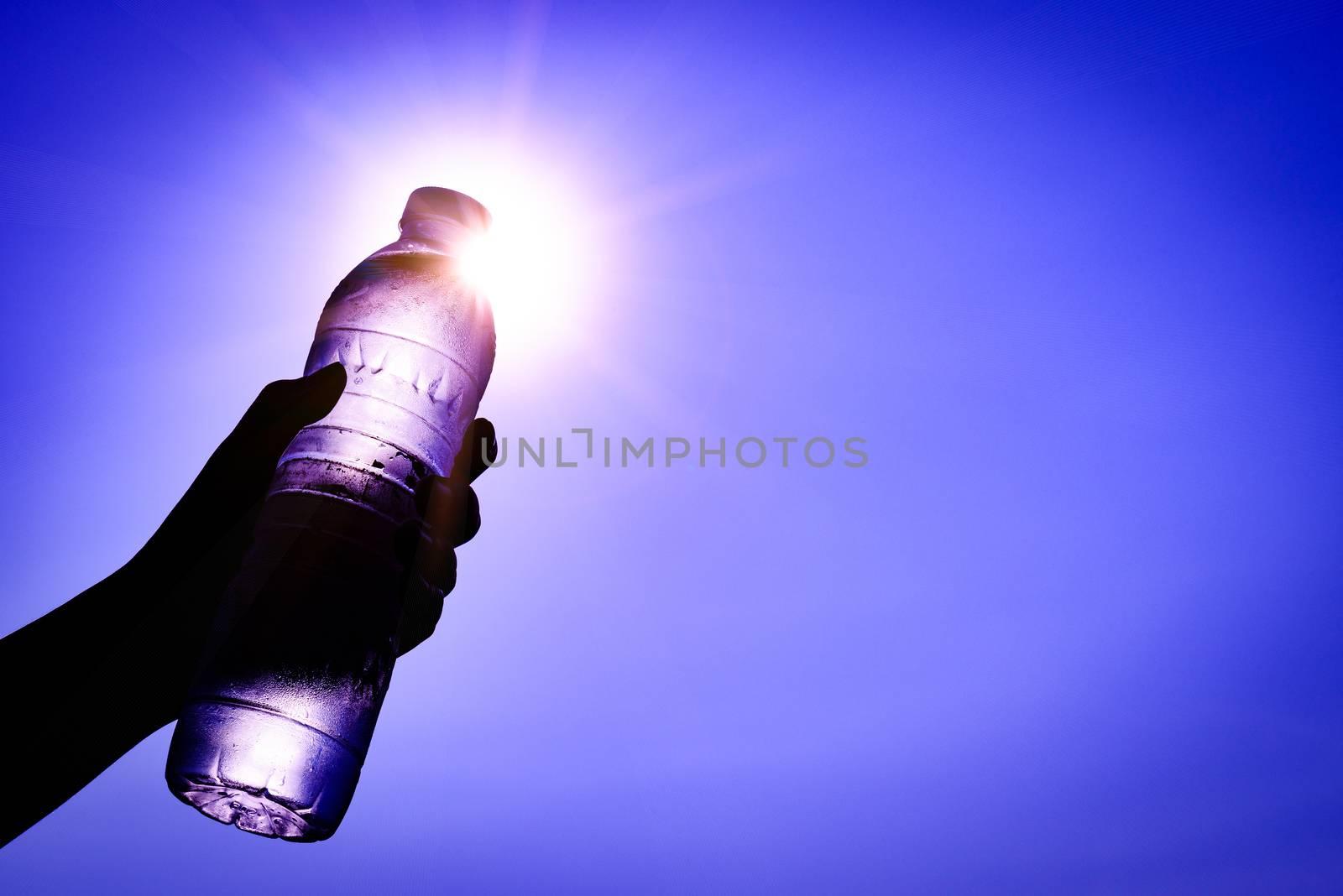 Silhouette of closeup Woman's hand holding plastic water bottle  by spukkato