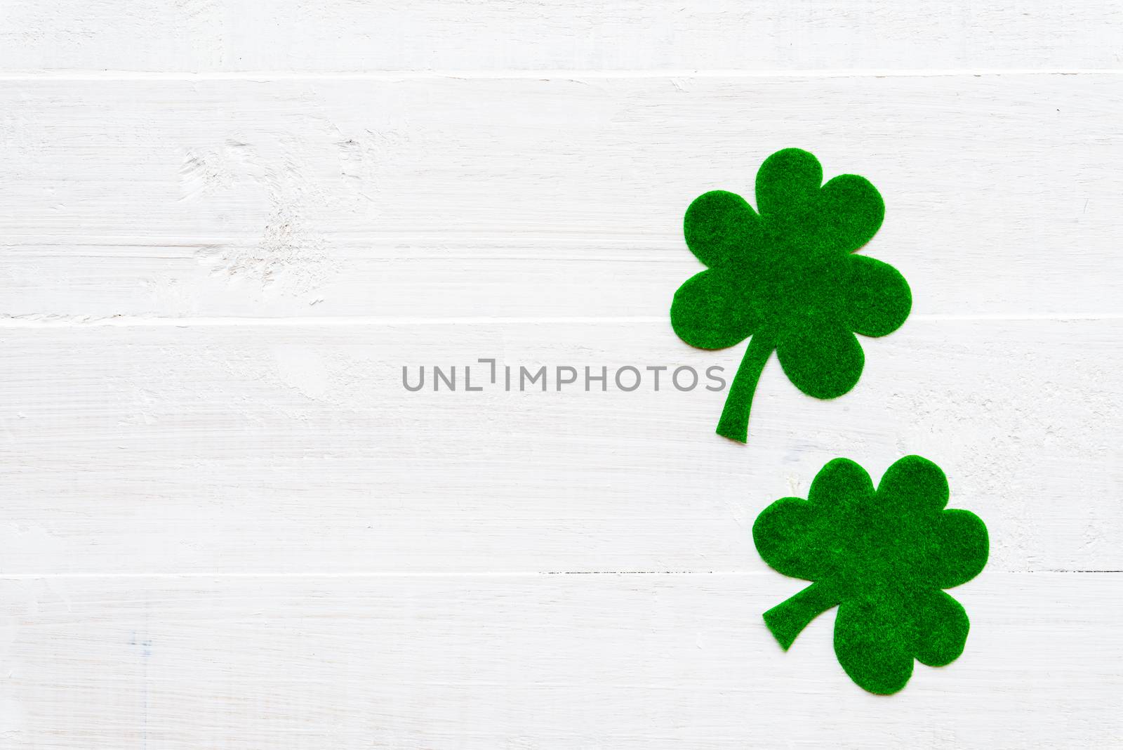 Happy St Patricks Day message on green paper clover and white wooden background