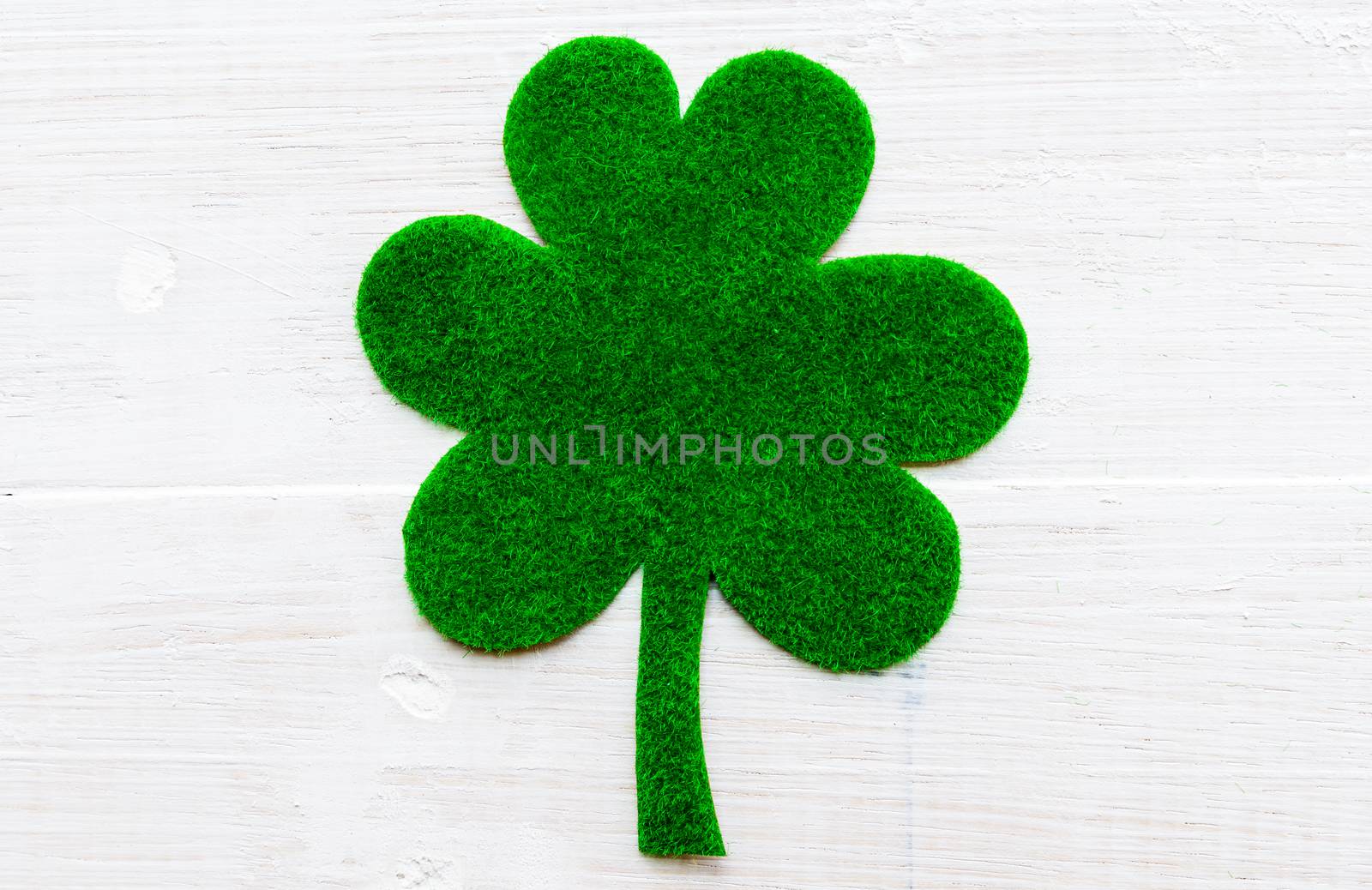 Happy St Patricks Day message on green paper clover and white wooden background