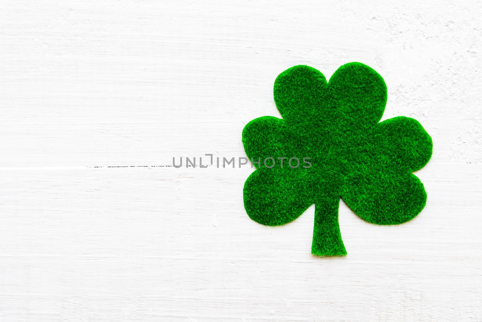 Happy St Patricks Day message on green paper clover and white wooden background