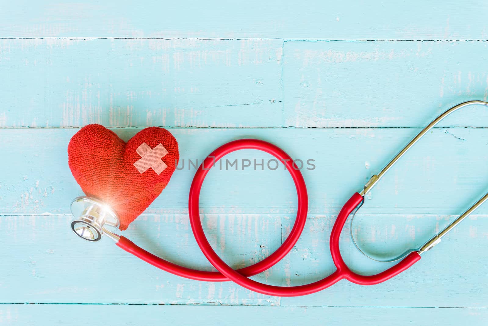 World health day, Healthcare and medical concept. Woman hand holding red heart with Stethoscope, notepad or notebook, thermometer and yellow Pill on Pastel white and blue wooden table background texture.